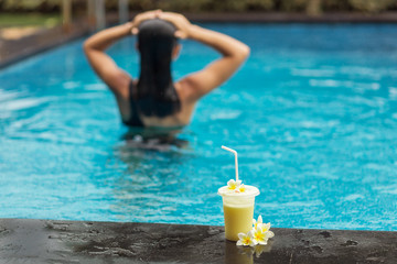 Back of woman with fuit shake in pool