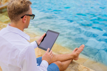Businessman with tablet computer by the pool