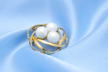 gold round brooch with pearls and gems isolated on silk
