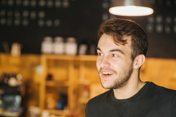 Portrait of handsome man. Always in good mood. Handsome young caucasian boy smiling and looking away while standing in front of the cafe outdoors