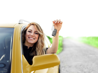 An attractive woman in the yellow car holds a car key in her hand.