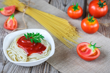 Spaghetti pasta with tomato sauce in plate and tomatoes on wooden table.