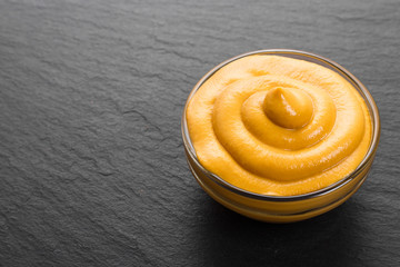 mustard in a bowl on a rustic background