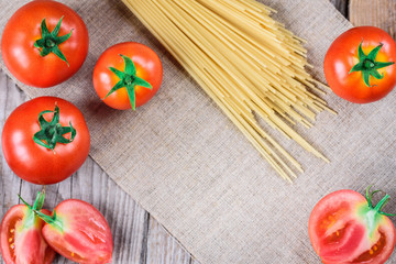 Spaghetti and tomatoes on wooden background