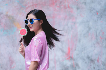 Obraz premium Woman with lollipop candy wearing pink fashion dress on colorful background.