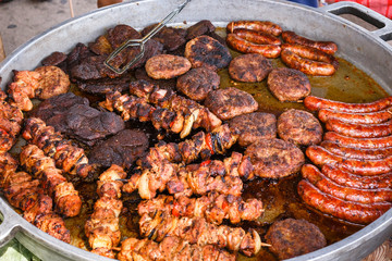 Delicious fresh meat is fried in a large frying pan in a street cafe.