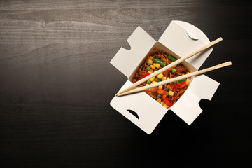 Carton box with delicious food on wooden table. Delivery service