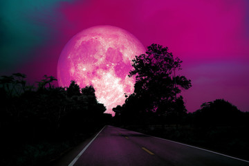 Fototapeta premium full pink moon on night sky over country road