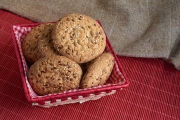 homemade oat cookies with sunflower seeds in and near red checkered basket on wooden table