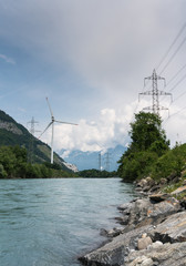 wind turbine and power lines on the banks of a river in a mountain valley