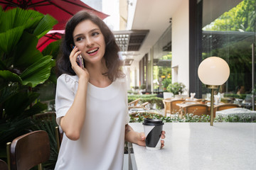 Charming woman with smile talking by mobile phone during rest in coffee shop