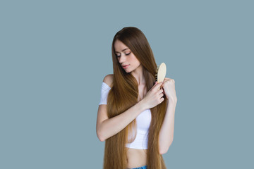 Concept of hair loss. Close up portrait of unhappy sad stressed young woman with long dry brown hair, isolated on grey background.