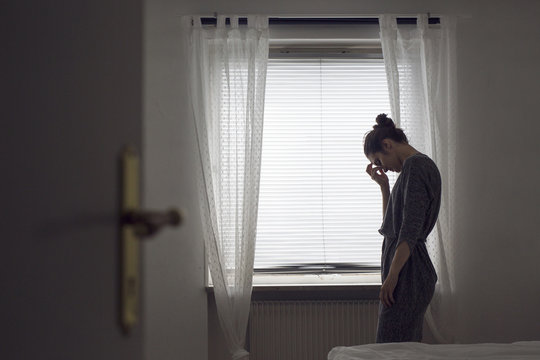 Pensive young woman standing by window