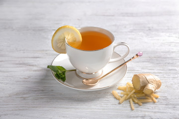 Cup of delicious tea with ginger and lemon on wooden table
