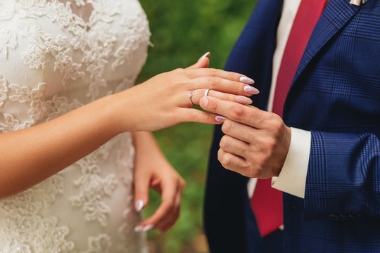 the groom placing a wedding ring on the brides hand