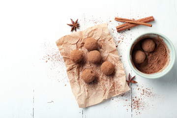 Tasty chocolate truffles on white wooden table