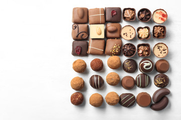 Different tasty chocolate candies on white wooden background