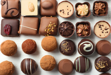 Different tasty chocolate candies on white wooden table