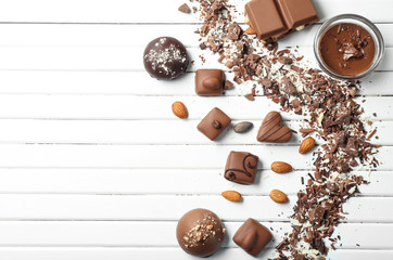 Different tasty chocolate candies on white wooden table
