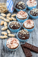 Tasty chocolate cupcakes on a grey wooden background with chocolate and nuts