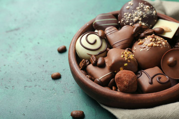 Bowl with different tasty chocolate candies on textured table