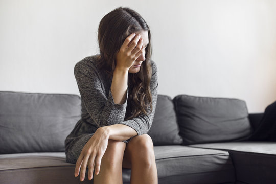Pensive young woman sitting on sofa