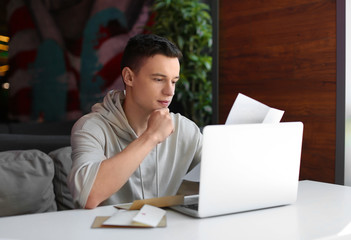 Young man reading letter at table in cafe. Mail delivery