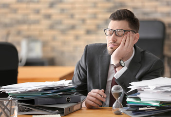 Tired mature businessman at table in office. Time management concept