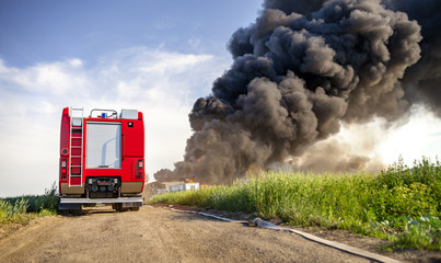 Red fire truck in action with landfill fire in background