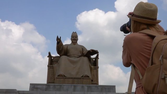 Young Female Traveler Taking Photo of King Sejong Monument at Gwanghwamun Square in Seoul, South Korea