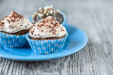 Tasty chocolate cupcakes on a grey wooden background with chocolate and nuts