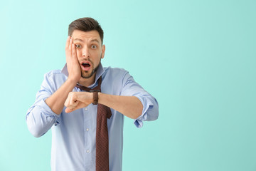 Man with wristwatch on color background. Time management concept