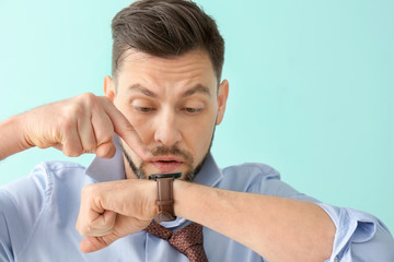 Man looking at wristwatch on color background. Time management concept