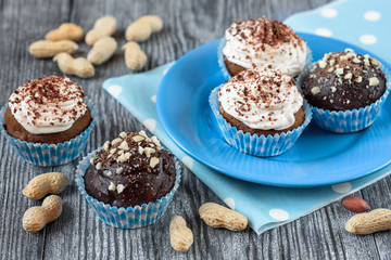 Tasty chocolate cupcakes on a grey wooden background with chocolate and nuts