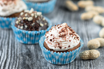 Tasty chocolate cupcakes on a grey wooden background with chocolate and nuts
