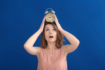 Mature woman with alarm clock on head against color background. Time management concept
