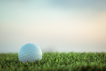 Golf ball on grass on sky background
