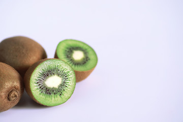 A kiwi fruit is sliced on a white background