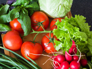 Vegetables and fresh herbs on a wooden board against the background of a kitchen table. Proper healthy eating. Vegetarianism.