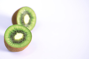 A kiwi fruit is sliced on a white background