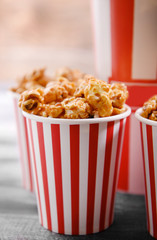 Paper buckets of tasty caramel popcorn on table