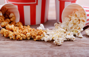 Paper buckets with scattered tasty popcorn on table