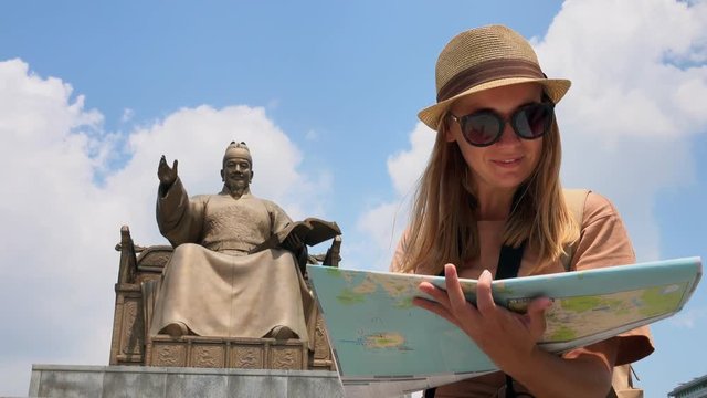 Female Tourist Looking at Map near King Sejong Monument at Gwanghwamun Square. Young Woman Exploring Historical Seoul District in South Korea