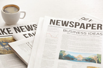 Morning newspapers and cup of hot coffee on white table