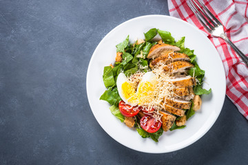 Caesar salad with chicken breast and tomatoes.