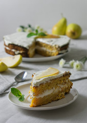 Homemade cake with pears on a table with a napkin, spoon and flowers in the sunlight