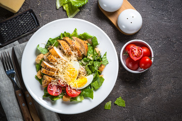 Caesar salad with chicken breast and tomatoes.