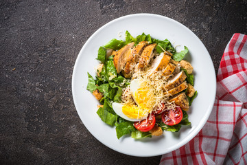 Caesar salad with chicken breast and tomatoes.