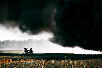 Firefighters standing under huge black cloud of smoke from the fire