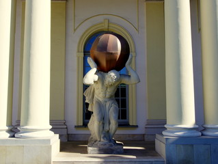 Atlas trzymający kulę - artystyczna rzeźba pomiędzy kolumnami przy wejściu do budynku - obrazy, fototapety, plakaty